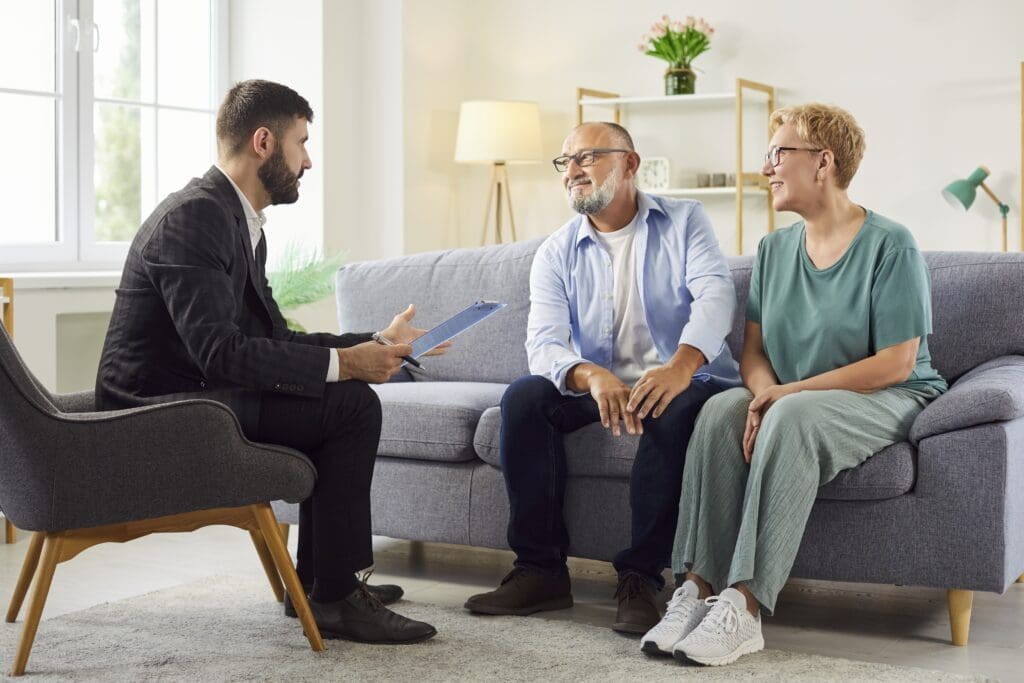 senior,couple,meets,an,advisor,on,couch,at,home,for